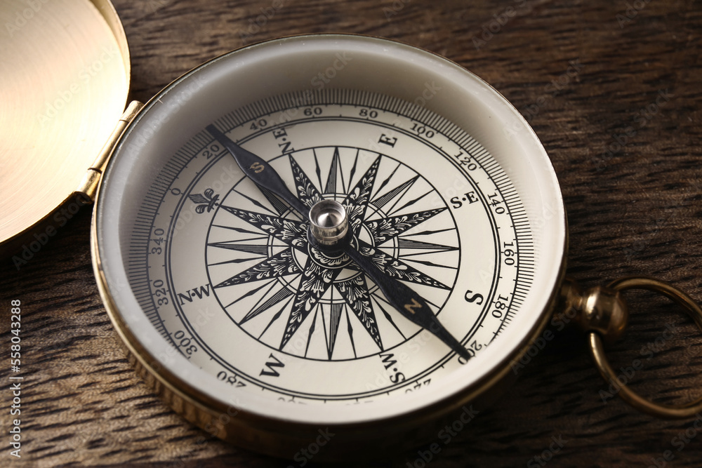 Golden compass on dark wooden background, closeup