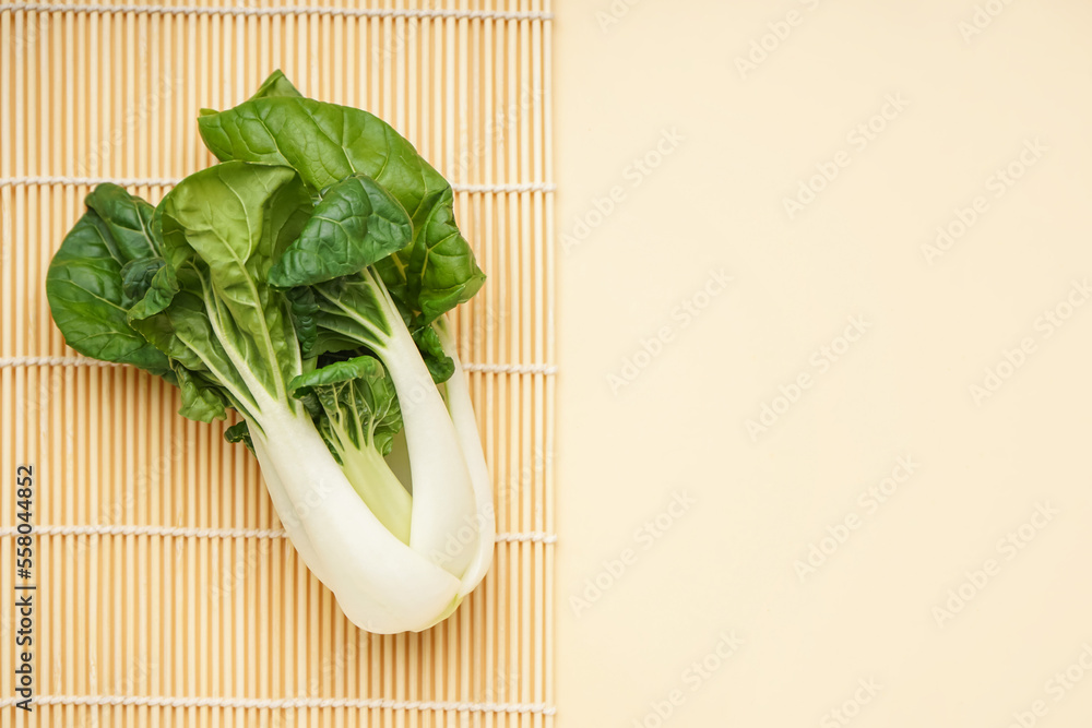 Bamboo mat with fresh pak choi cabbage on color background