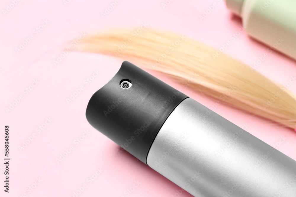 Hair spray with blonde strand on pink background, closeup