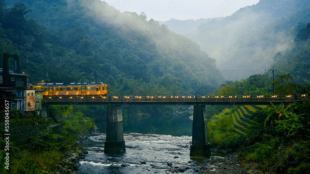 Trains pass over the bridge. The station next to a stream in a foggy valley. Sandiaoling Railway Sta