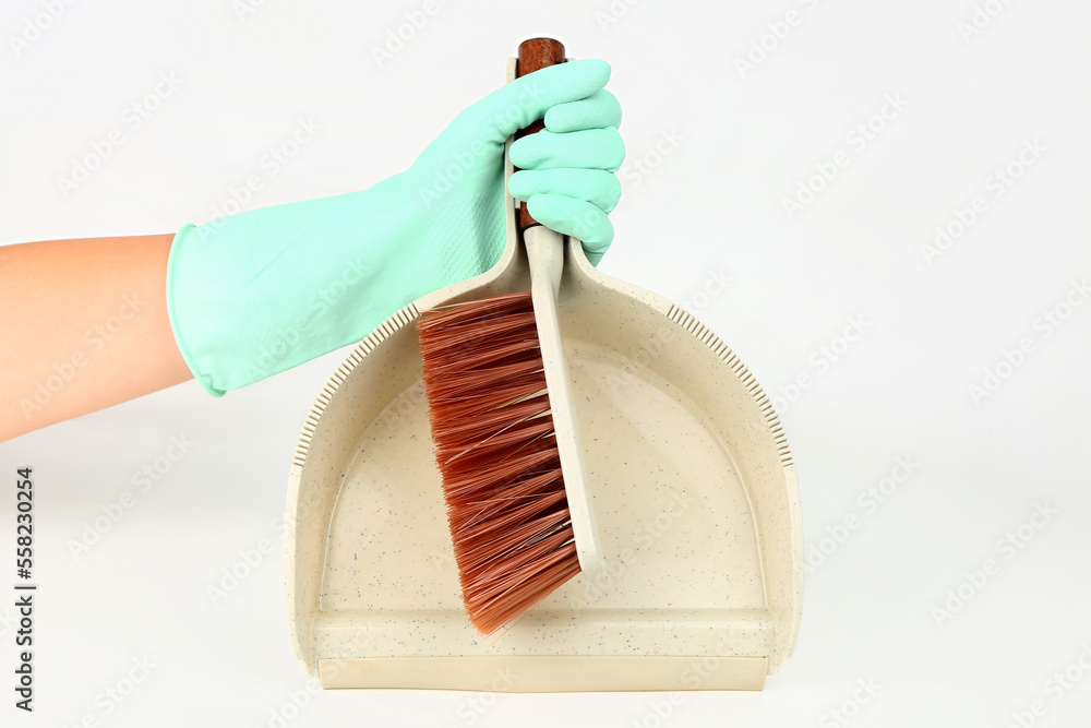 Female hand in rubber glove with dustpan and brush on white background, closeup