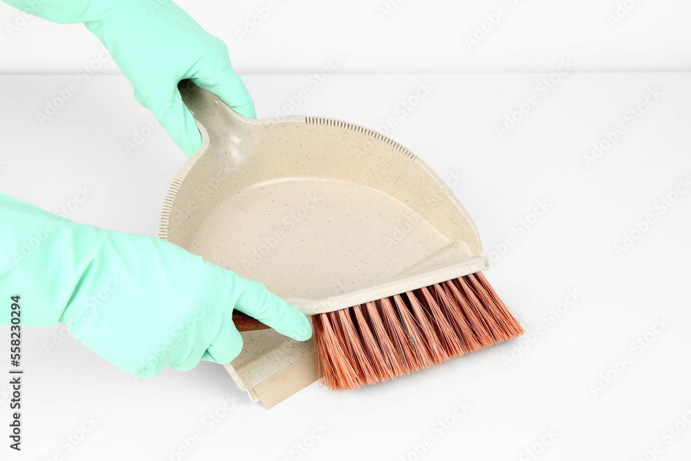 Female hands in rubber gloves with dustpan and brush on white background