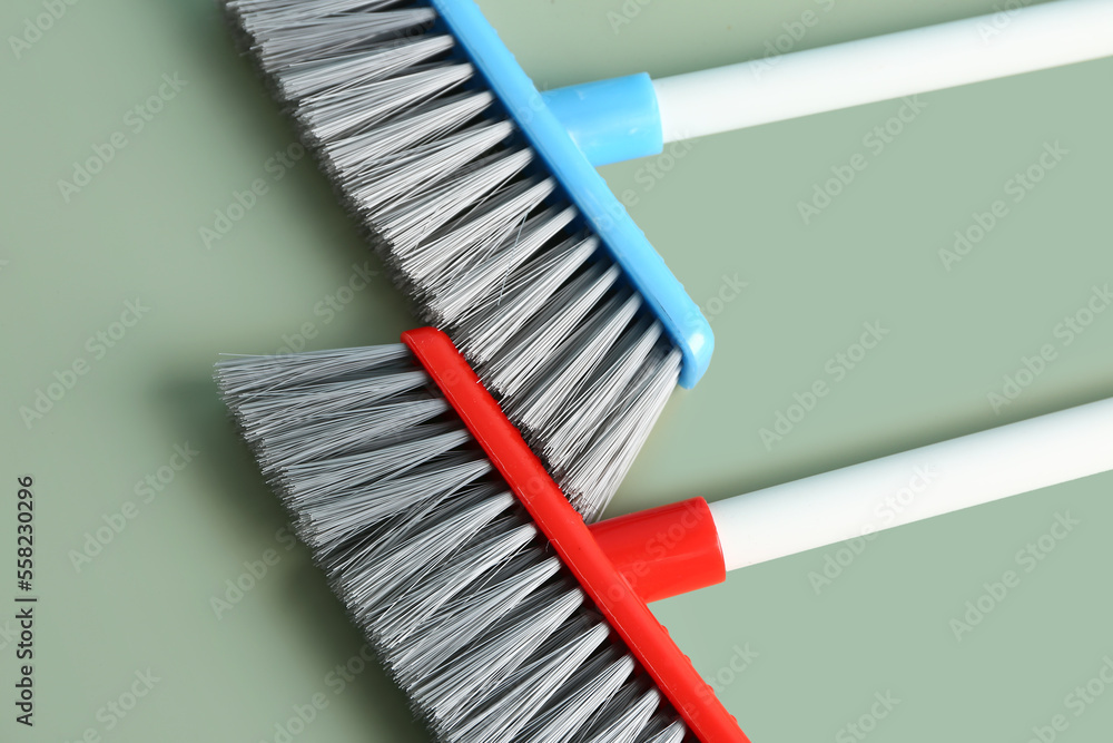 Two cleaning brooms on color background, closeup