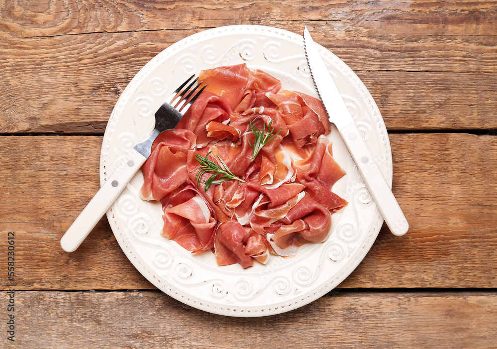 Plate with slices of delicious ham on wooden background