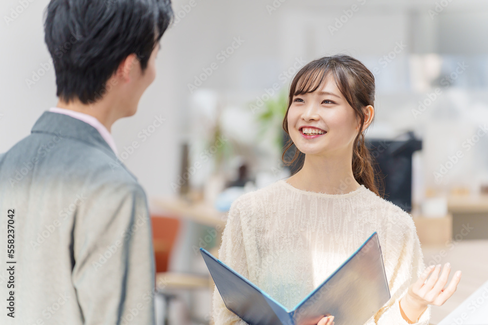 オフィスで立ち話をする若い男女