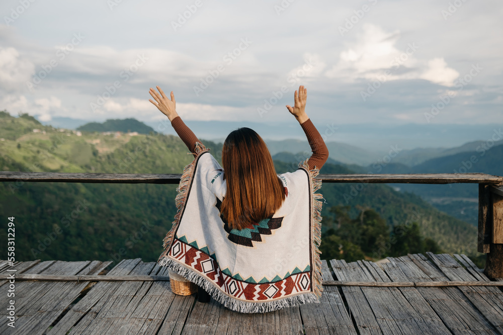  Female traveler sitting and looking at a beautiful mountain,flower field and nature view.