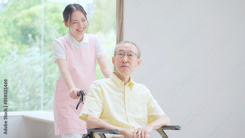 車椅子に乗った高齢者を介助する女性ヘルパー