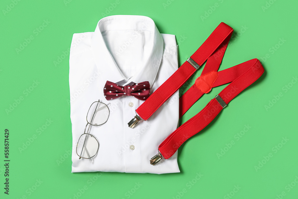 Male shirt, bow tie, eyeglasses and suspenders on green background