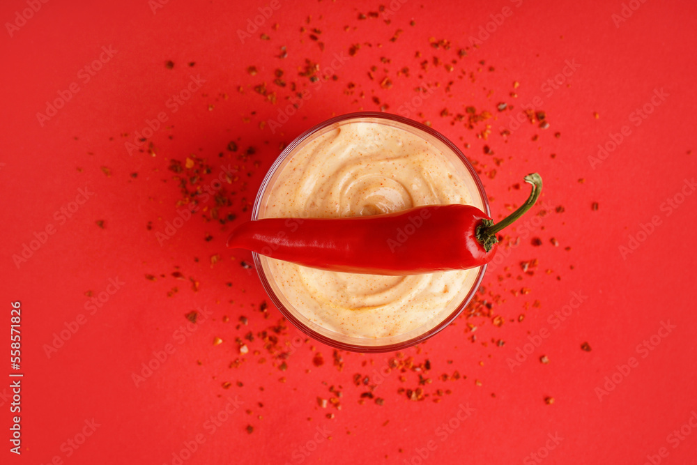 Bowl of tasty chipotle sauce and fresh jalapeno pepper on red background