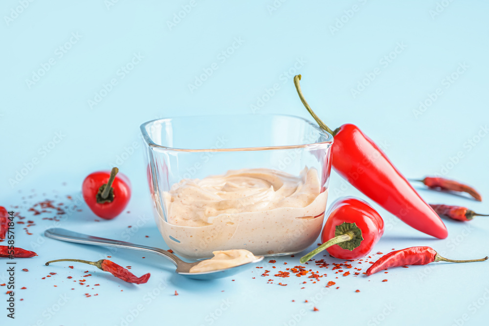 Bowl of tasty chipotle sauce and jalapeno peppers on color background