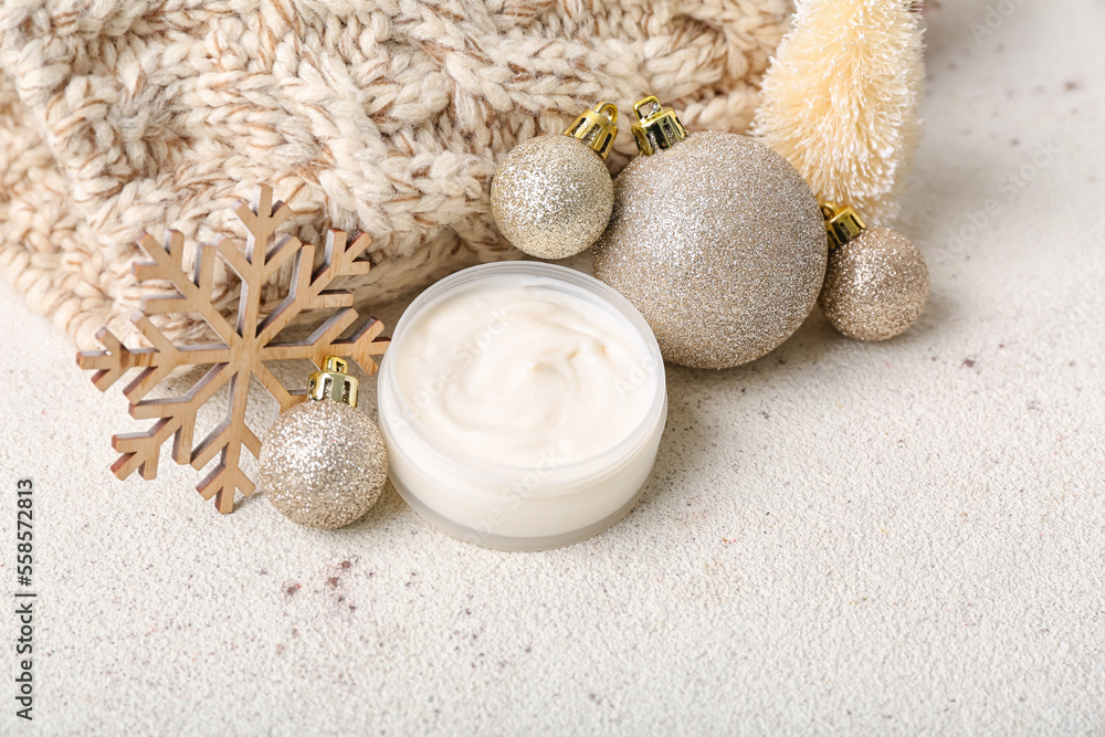 Jar of cream, Christmas decorations and warm hat on light background