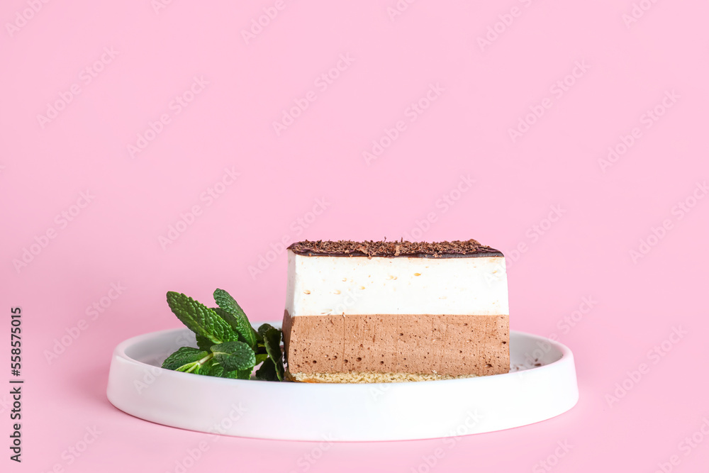 Plate with piece of birds milk cake and mint leaves on pink background