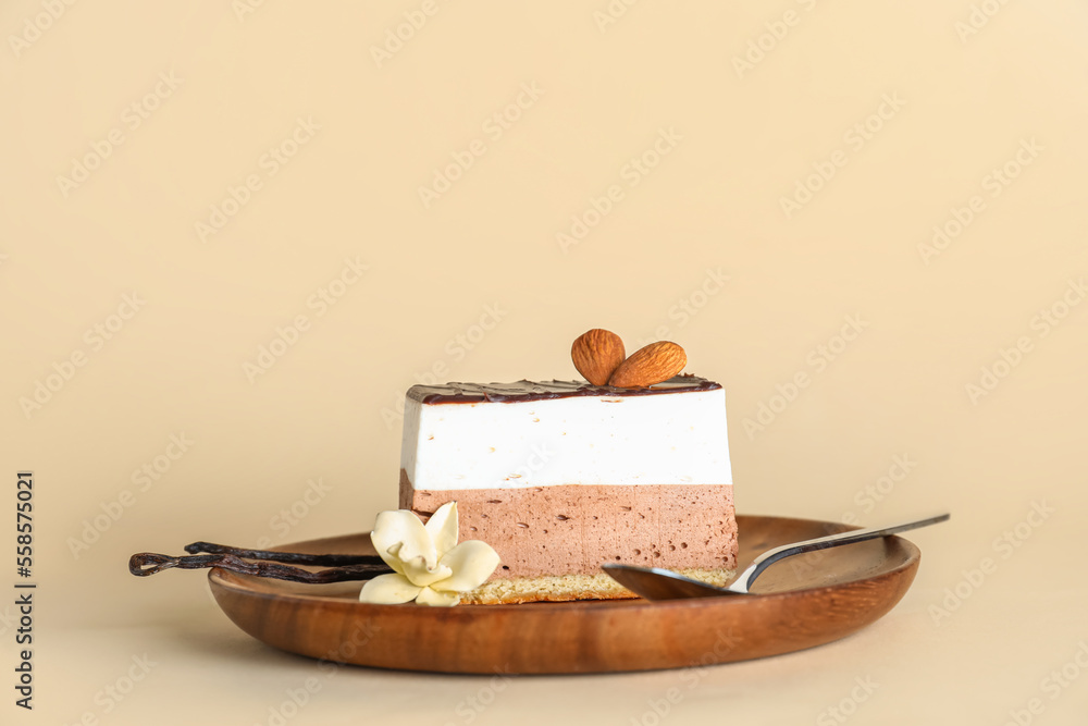 Wooden plate with piece of birds milk cake, almond nuts, vanilla and spoon on beige background