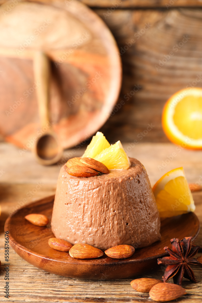 Plate with delicious chocolate pudding, almond nuts, anise and orange slices on wooden table