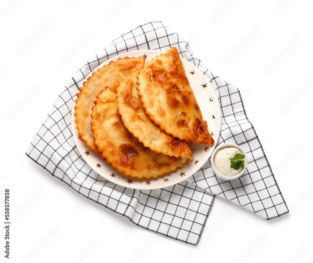 Plate with tasty chebureks, sauce and kitchen towel on white background