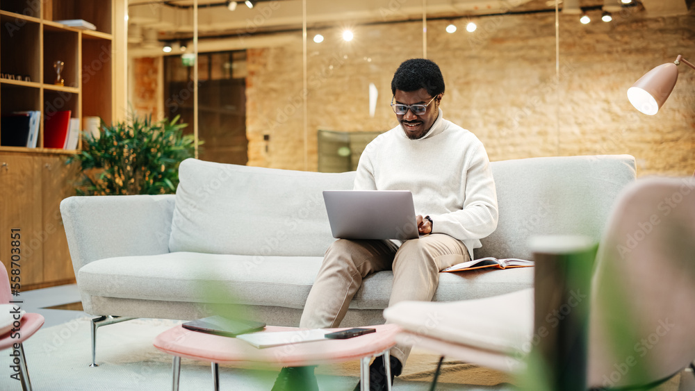 Portrait of Black Creative Young Man Working on a Laptop in Casual Office During Day. Male Recruiter