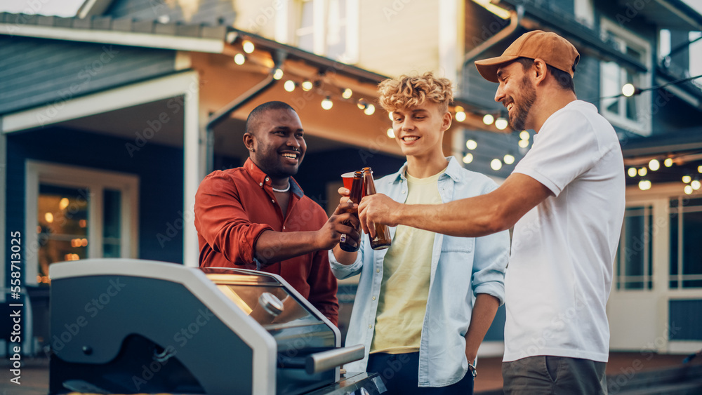 Young Man in a Cap Showing Off His Modern Fire Grill to Two Diverse Mates at a Garden Barbecue Party