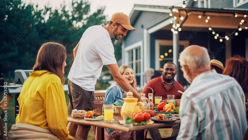 Young Adult Man Bringing Prepared Barbecue Meat Burgers to the Table with Young and Senior Relatives