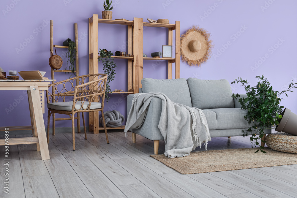 Interior of messy living room with shelf units, sofa and overturned houseplant