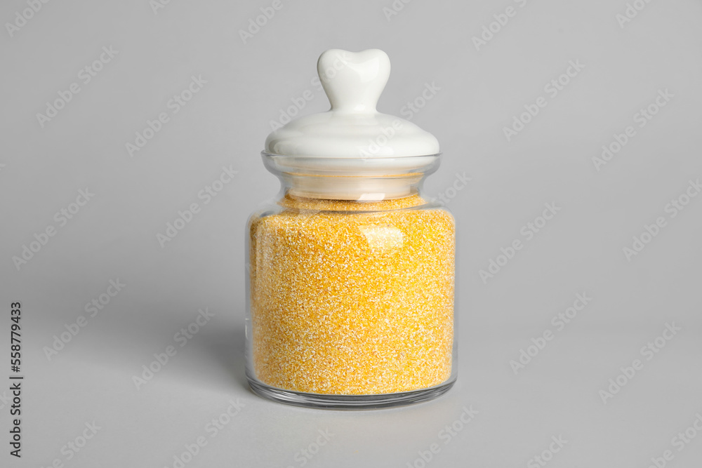 Glass jar of corn grits on white background