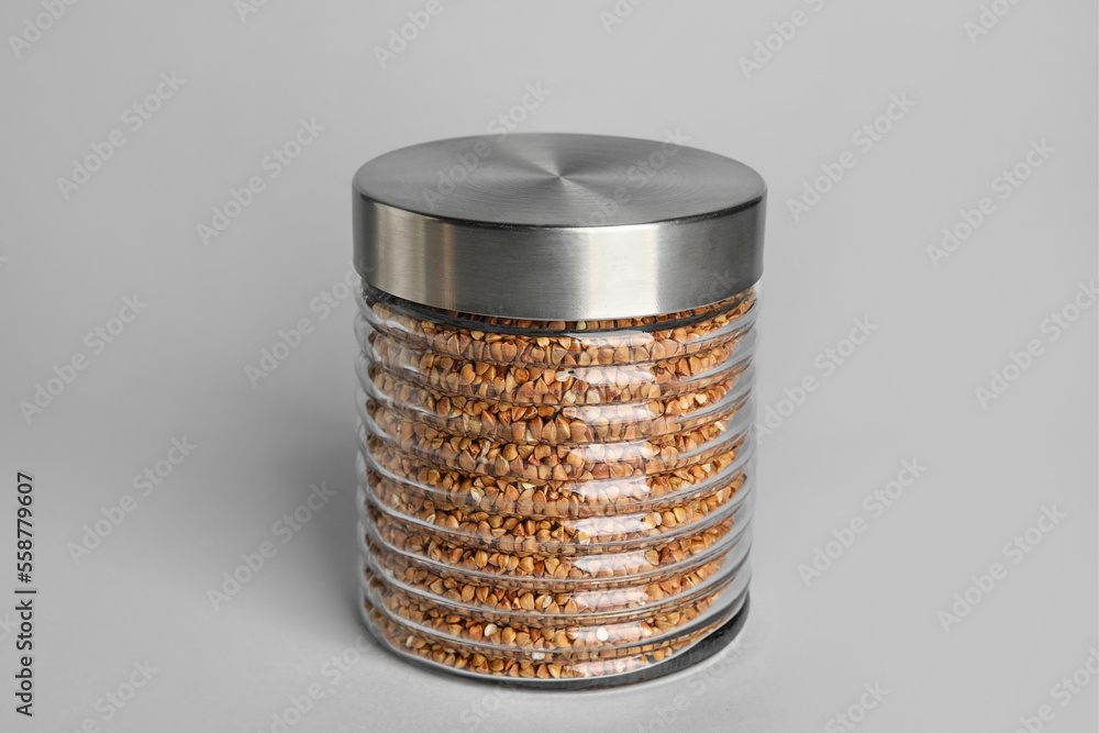 Glass jar with buckwheat on white background