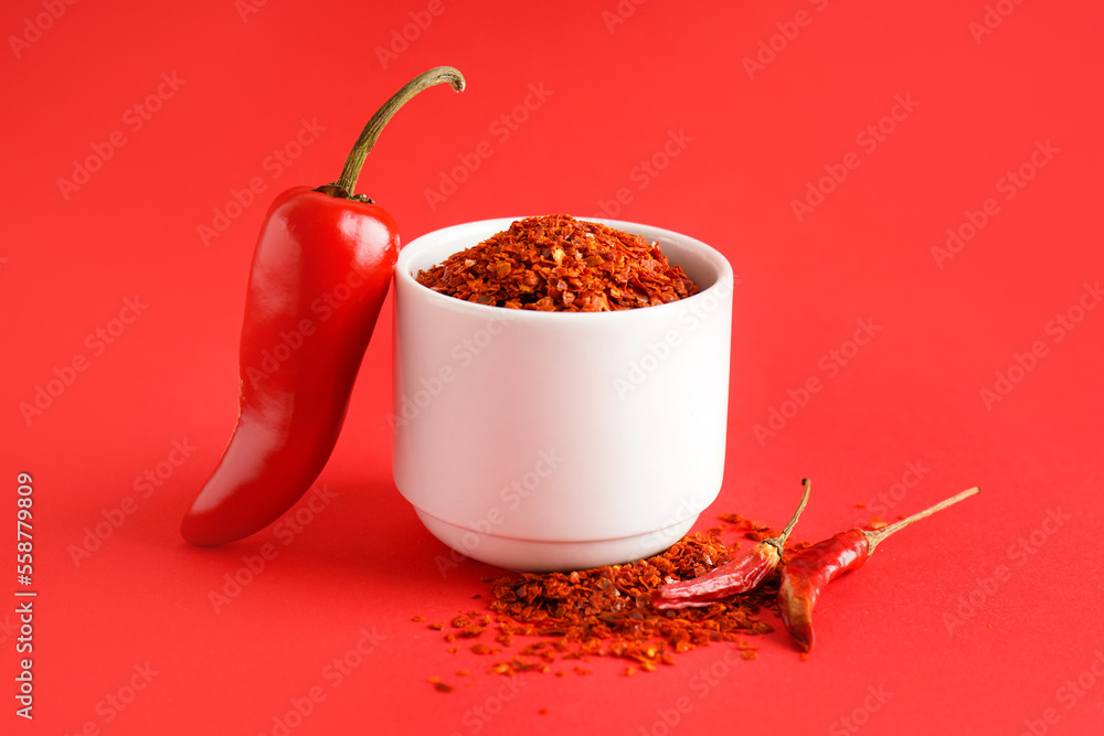 Bowl of chipotle chili flakes on red background