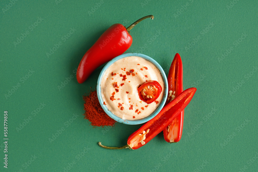 Bowl of tasty chipotle sauce and fresh jalapeno peppers on color background