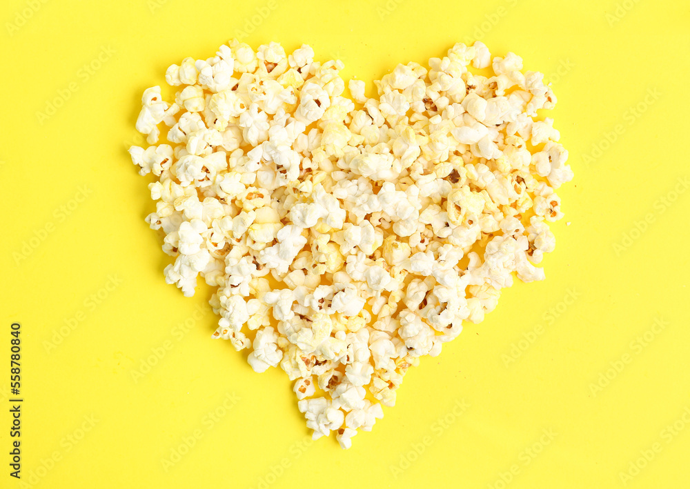 Heart made of tasty popcorn on yellow background