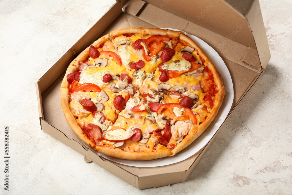 Cardboard box with delicious pizza on light background