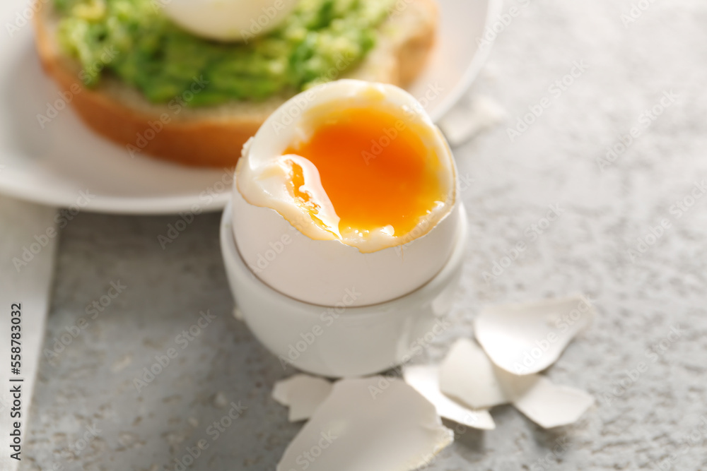 Holder with soft boiled egg and shell on grey table