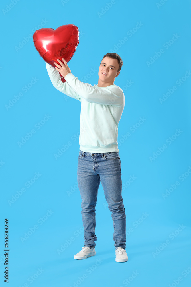 Young man with balloon for Valentines Day on blue background