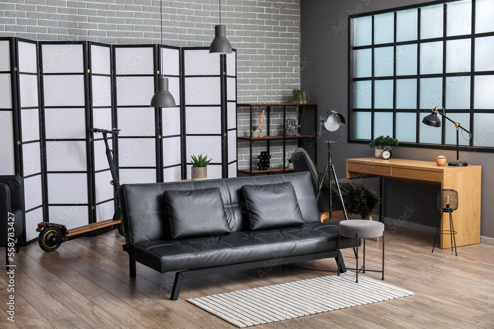 Interior of modern office with black couch, workplace and scooter