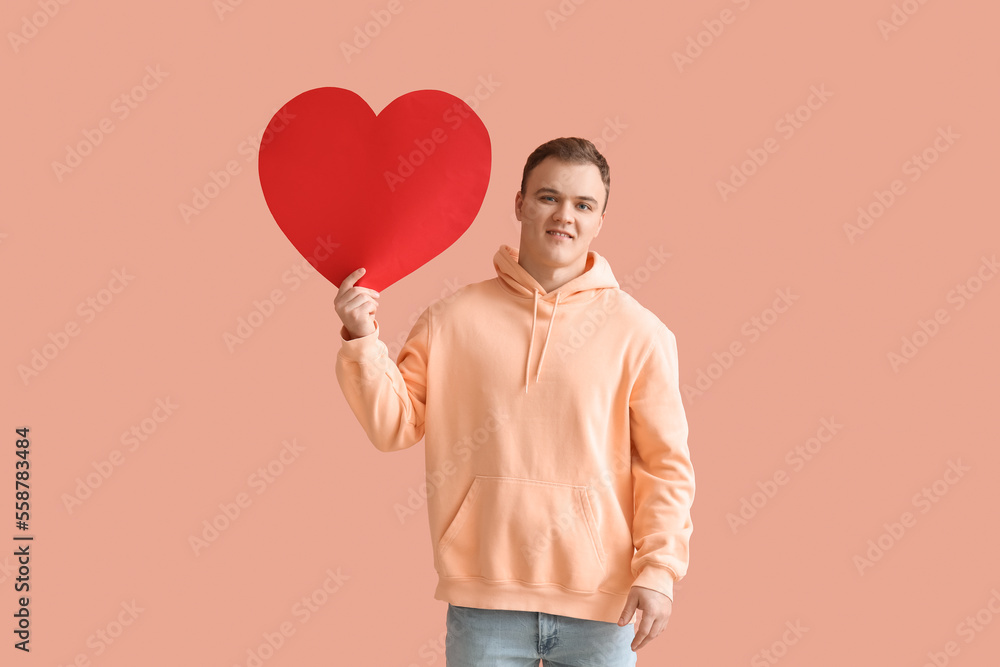 Young man with big paper heart for Valentines Day on beige background