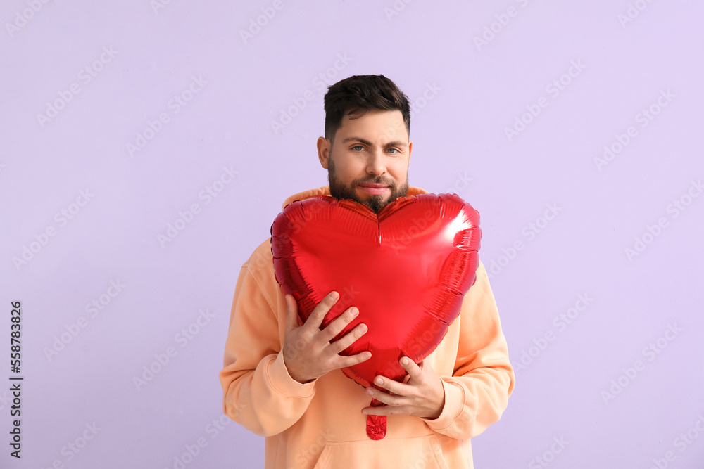 Young bearded man with balloon for Valentines Day on lilac background