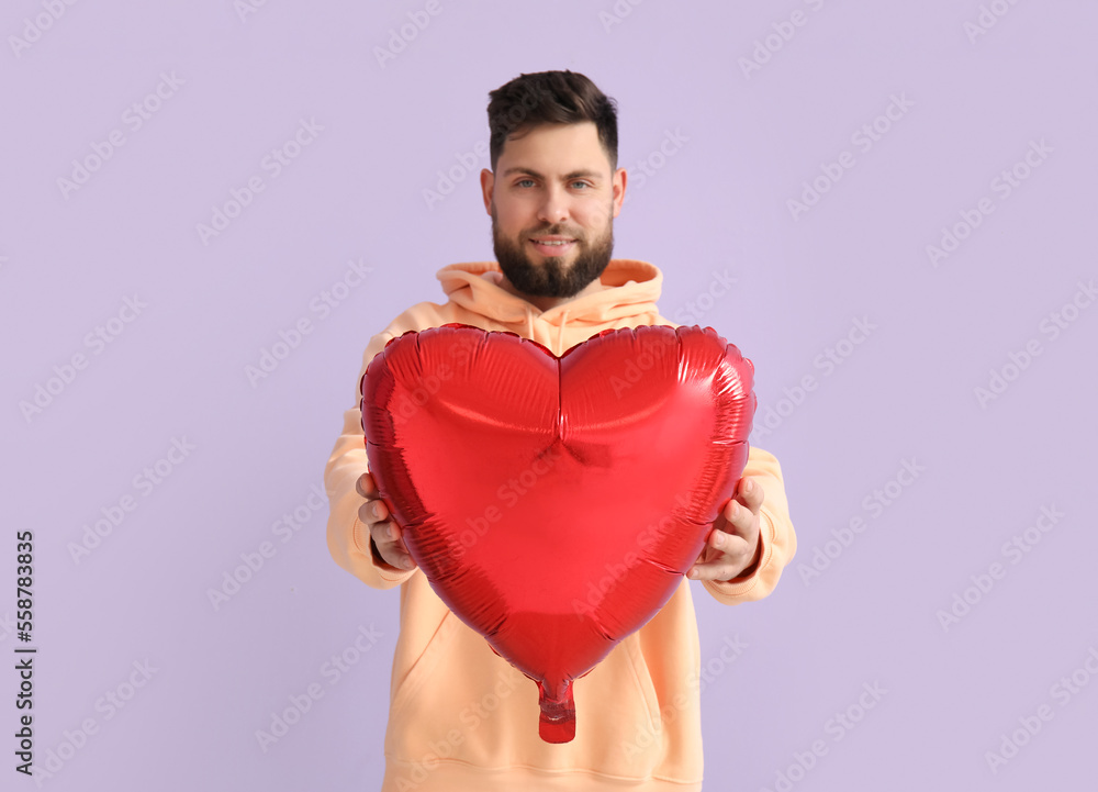 Young bearded man with balloon for Valentines Day on lilac background