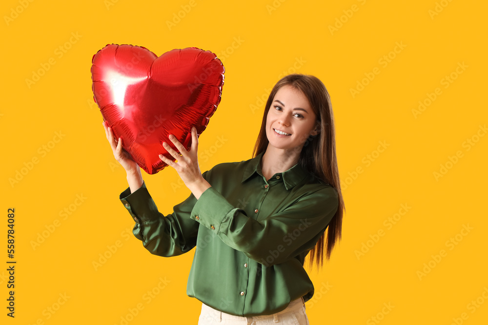 Young woman with balloon for Valentines Day on yellow background