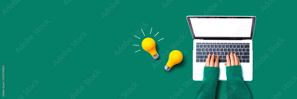 Person using a laptop computer and light bulbs - Flat lay