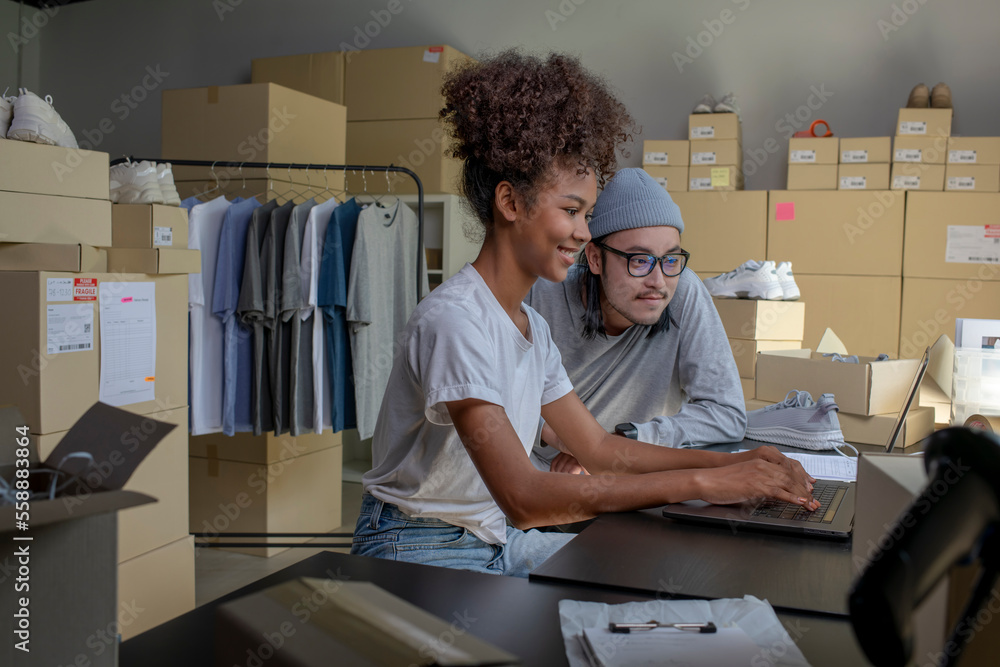 Mixed race couple of Asian man and African-American woman online seller confirming orders from custo