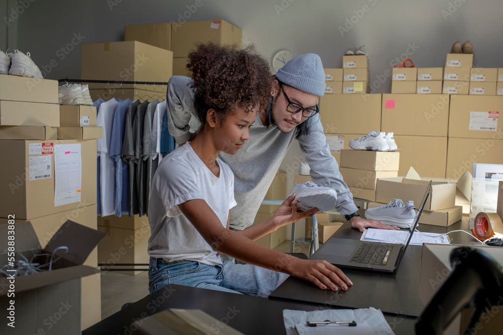 Mixed race couple of Asian man and African-American woman online seller confirming orders from custo