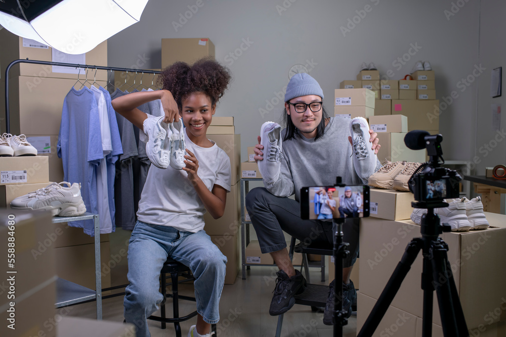 Mixed race couple of Asian man and African-American woman blogger or vlogger looking at camera revie