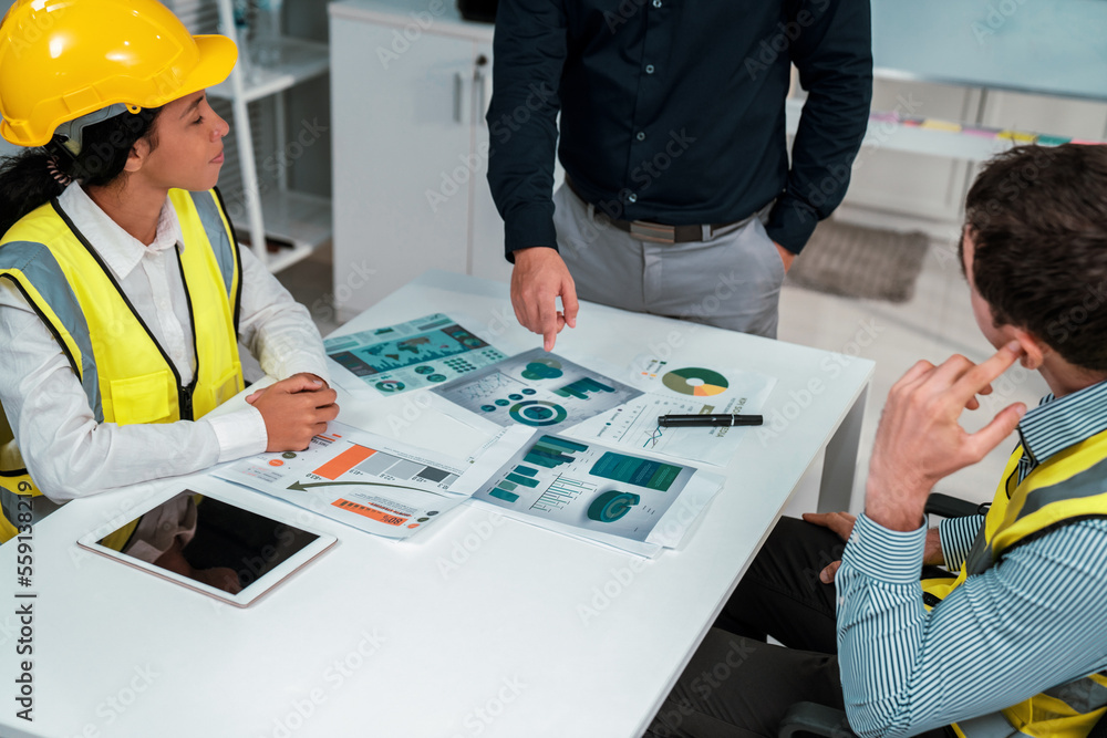 Engineers and competent employer discussing plans and blueprints together with tablet in the office.