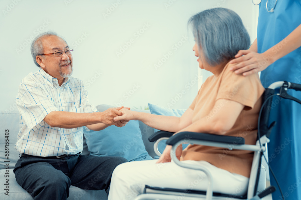 A contented senior couple and their in-home nurse. Elderly female in wheelchair with her young careg