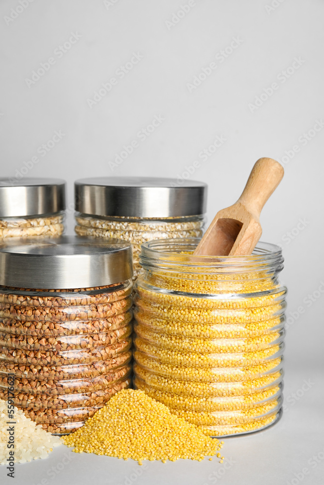 Glass jars with different cereals on white background, closeup