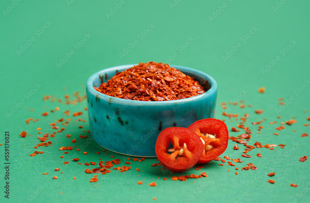 Bowl of chipotle chili flakes on green background