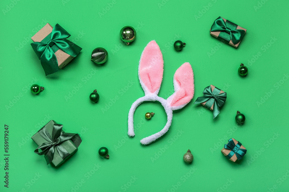 Bunny ears with Christmas balls and gifts on green background