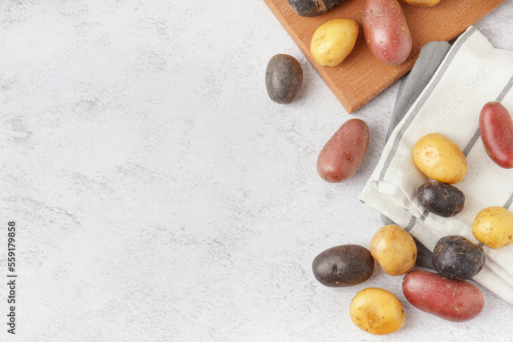 Different types of raw potatoes on light background