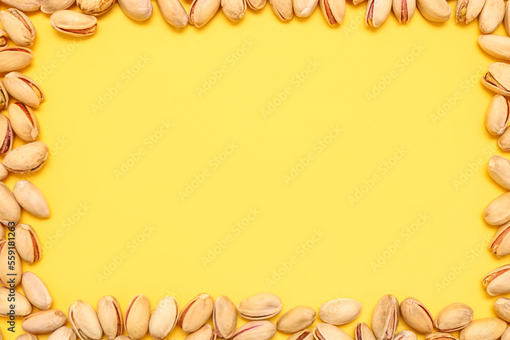 Frame made of tasty pistachio nuts on yellow background