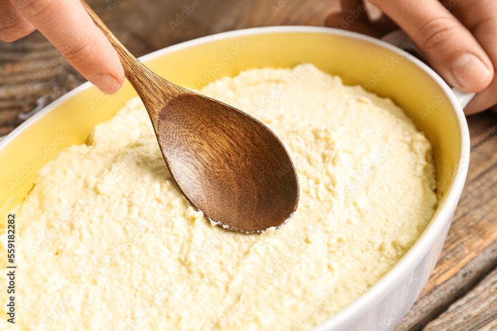 Woman preparing cheese pie on wooden table