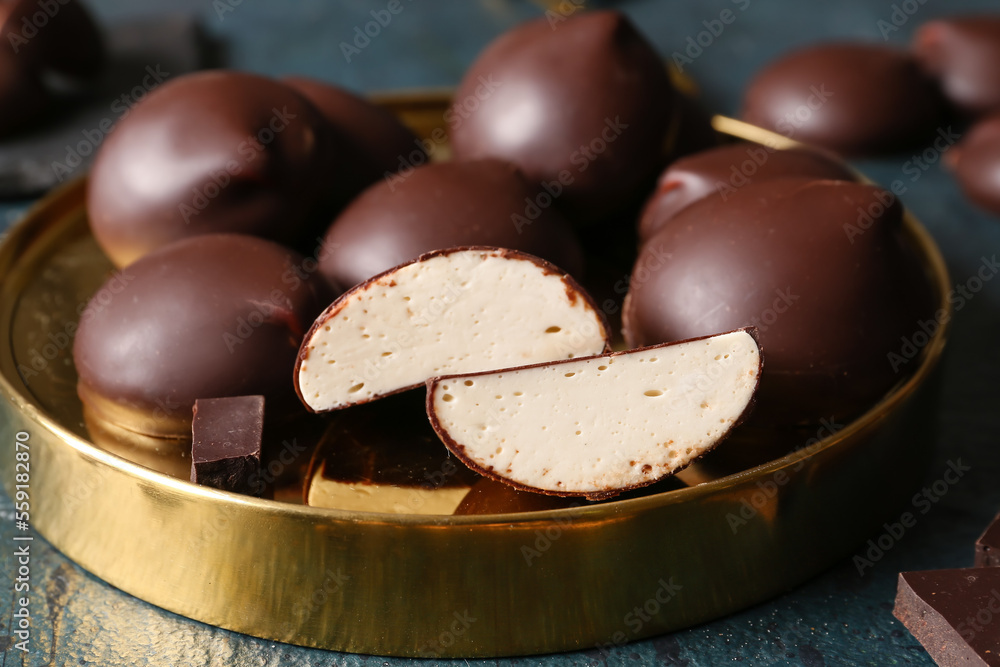 Metallic board with sweet chocolate birds milk candies on dark background, closeup