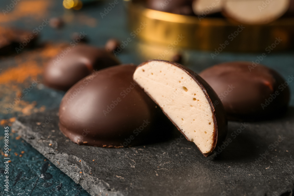 Plate with tasty birds milk candies on dark background, closeup